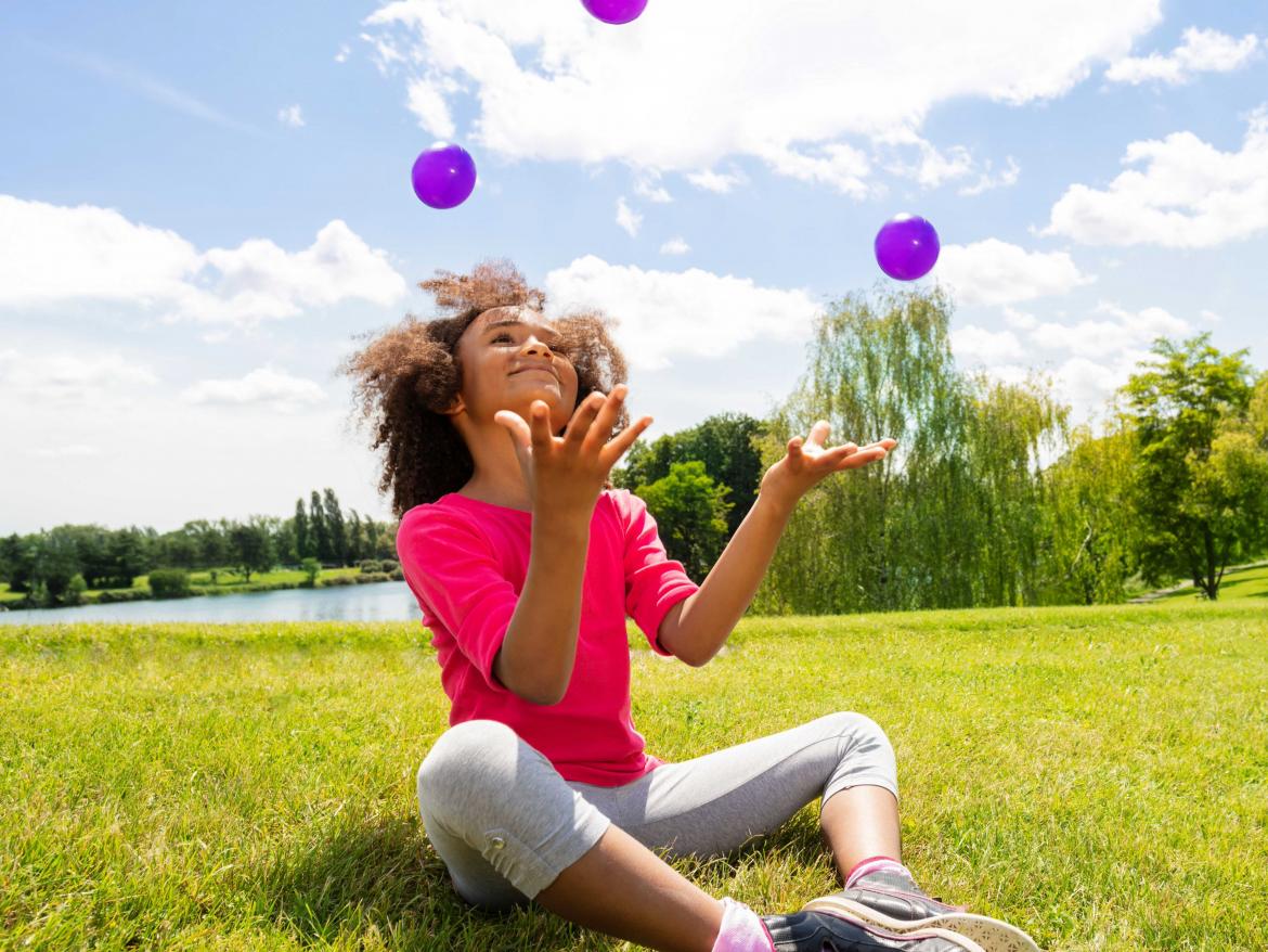 enfant jonglant avec des balles violettes