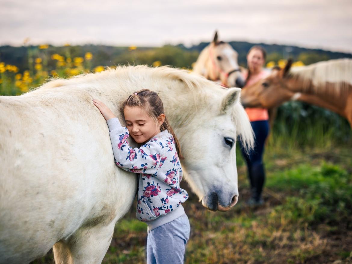 enfant faisant un calin a une cheval