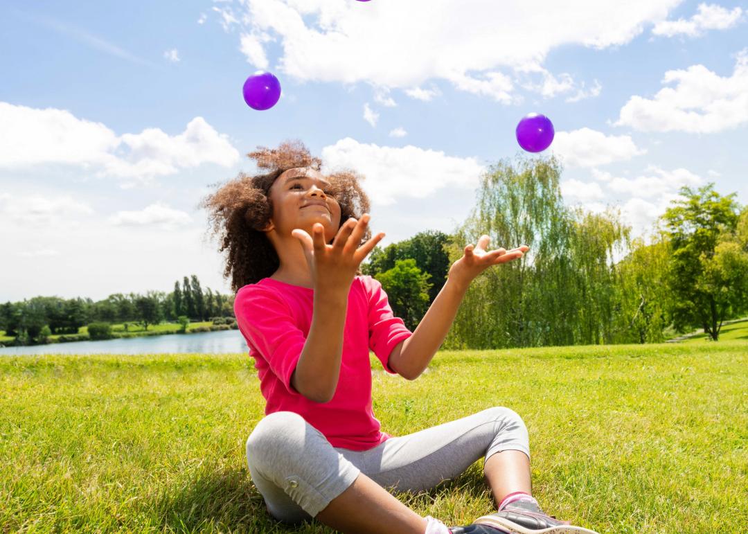 enfant jonglant avec des balles violettes